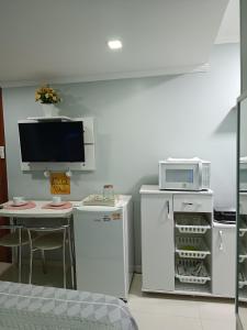 a kitchen with a refrigerator and a table with a microwave at ** SUITE PRIVATIVA PRAIA DO FORTE CABO FRIO ** in Cabo Frio