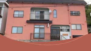 a pink apartment building with a ramp in front of it at SPR港家 in Kamuenai