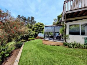 a garden with a house with a lawn at Garden Bliss & Bird Sanctuary in Paihia Estuary in Paihia