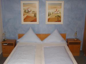 a bedroom with a white bed with two pictures on the wall at Hotel Garni Löhr in Landau an der Isar