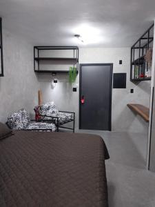 a bedroom with a bed and a chair and a door at FLAT PALLADIUM - DE FRENTE - novo in São Vicente