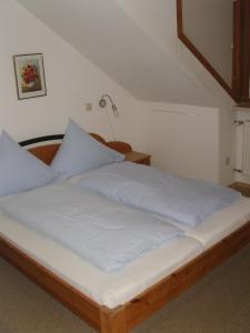 a bed with white sheets and blue pillows at Hotel Garni Löhr in Landau an der Isar