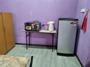 a small table with a refrigerator next to a purple wall at E.R. BUDGET INN in Kota Bharu