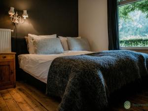 um quarto com uma cama com um cobertor e uma janela em Spacious Farmhouse near Forest in Heeze-Leende em Leende