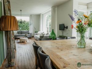 een woonkamer met een tafel met een vaas met bloemen bij Majestic, large holiday home near Leende, detached and located between meadows and forests in Leende