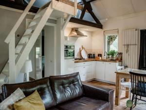 a living room with a leather couch and a kitchen at Spacious Farmhouse near Forest in Heeze-Leende in Leende