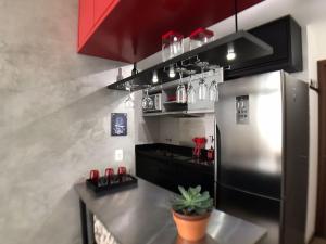 una cocina con nevera de acero inoxidable y armarios rojos en Maravilhoso Loft vista mar OCEANVIEW en Niterói