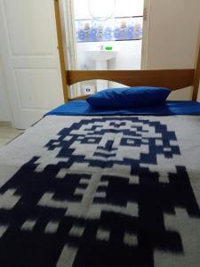 a bed with a blue and white blanket on it at Small House in Cusco
