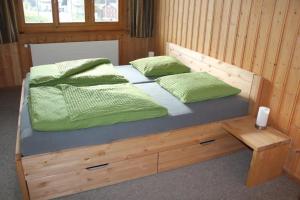 una cama de madera con 2 almohadas verdes. en Tgesa Tieni en Sedrun