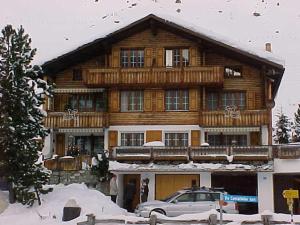 ein großes Holzhaus mit einem Auto davor in der Unterkunft Tgesa Tieni in Sedrun