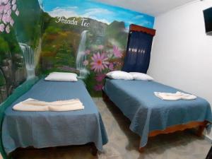 2 Betten in einem Zimmer mit Wandgemälde in der Unterkunft Posada TEO in Xilitla