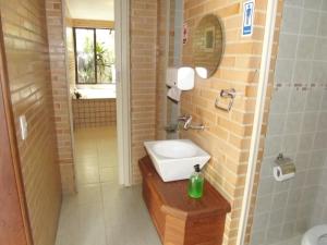 uma casa de banho com um lavatório e um chuveiro com um espelho. em Pousada Pé da Tartaruga em Teresópolis