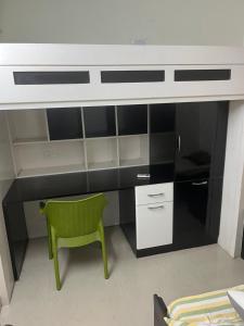 a kitchen with a green chair and a desk at Affordable Orchid service apartment in korattur, Chennai in Chennai