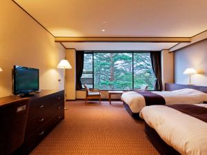 a hotel room with two beds and a flat screen tv at Jodogahama Park Hotel in Miyako