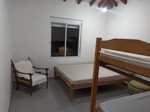 sypialnia z łóżkiem, krzesłem i oknem w obiekcie Casa em Ubatuba. w mieście Ubatuba