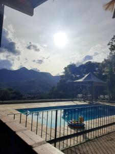 a swimming pool with an umbrella and a view of mountains at Pousada Pé da Tartaruga in Teresópolis