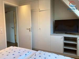 a bedroom with a bed and a tv on a wall at Haus Achterhus 215 - Wohnung 11 "Sandkörnchen" in Juist