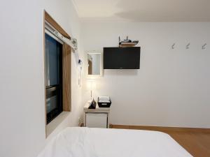 a white bedroom with a bed and a window at K9 Myeongdong Hotel in Seoul