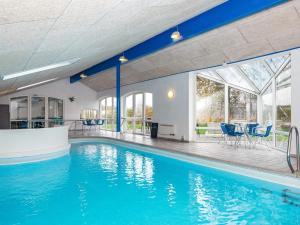 亨能史特蘭德的住宿－12 person holiday home in Henne，一座带蓝色椅子的别墅内的游泳池