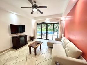 a living room with a couch and a flat screen tv at The Oaks Tamarindo Primer piso, 22, 49, 73 in Tamarindo