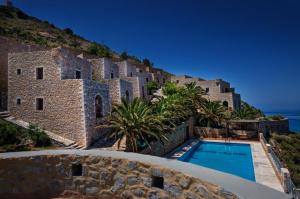 a building with a swimming pool next to the ocean at Limeni Village in Limeni
