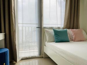 Una cama con almohadas sentada frente a una ventana en Sakan 5-Star Quality Condotel en Manila