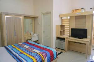 Schlafzimmer mit einem Bett und einem Schreibtisch mit einem TV in der Unterkunft Musdalifah Hotel in Nambakor