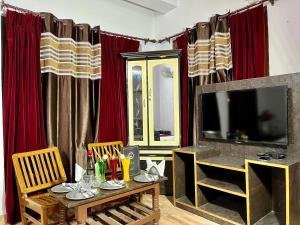 a living room with a table and a television at Vanshika homes Near mall road in Kasauli