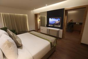 a hotel room with a bed and a flat screen tv at Pharos Hotels in Chennai
