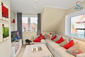 a living room with a white couch with red pillows at Haus Achterhus 213 - Wohnung 13 "rote Krabbe" in Juist