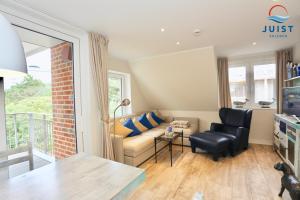 a living room with a couch and a chair at Haus Achterhus 214 - Wohnung 14 "blauer Anker" in Juist