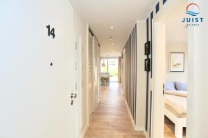 a hallway of a house with white walls and wooden floors at Haus Achterhus 214 - Wohnung 14 "blauer Anker" in Juist