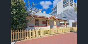una cerca amarilla frente a una casa pequeña en Emu Backpackers Perth - note - Valid passport required to check in, en Perth