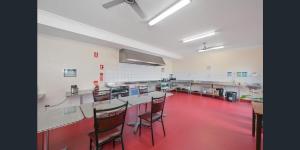 Habitación con suelo rojo y sillas. en Emu Backpackers Perth - note - Valid passport required to check in, en Perth