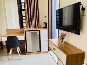 a room with a tv and a desk with a chair at EVA Hotel in Hue