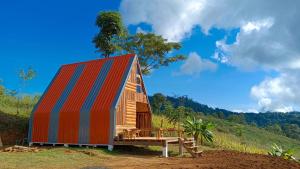 una pequeña casa con un techo colorido en una colina en ไร่นิธิสุนทร nithisoonthon farmstay en Mae Hong Son