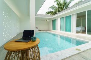 a laptop sitting on a table next to a swimming pool at The Pin Boutique Pool Villa Krabi in Ao Nang Beach
