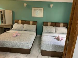 two beds with pink slippers on them in a bedroom at 2 bedroom 2 bathroom Paul Serene Ramin F201 in Genting Highlands