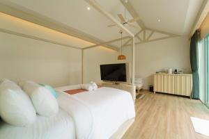 a bedroom with a white bed and a flat screen tv at The Pin Boutique Pool Villa Krabi in Ao Nang Beach