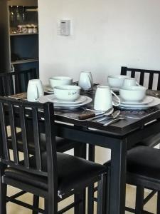 - une table à manger noire avec des bols et des chaises blancs dans l'établissement La casita del árbol, amplia y cómoda en barrio familiar, à Campeche