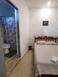 a bedroom with a bed and a bathroom with a toilet at La casita del árbol, amplia y cómoda en barrio familiar in Campeche
