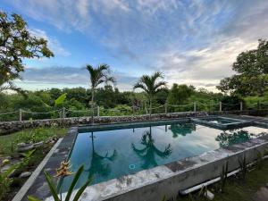 a swimming pool in a resort with trees in the background at Sanctum Hotel and Dive- Nusa Penida in Nusa Penida