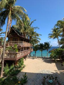 Bamboo House Beach Lodge & Restaurant في بويرتو غاليرا: منتجع على الشاطئ يوجد به نخل والمحيط