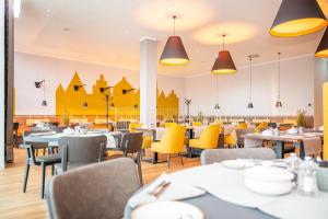 une salle à manger avec des tables et des chaises jaunes dans l'établissement VIA PLAZA Hotel Meppen, à Meppen