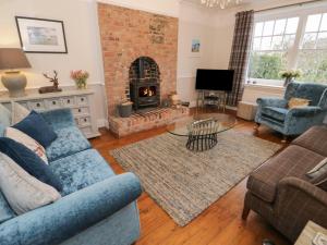 a living room with a blue couch and a fireplace at Moss Bank House in Conwy