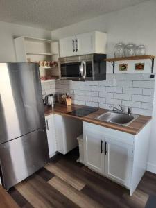 een keuken met witte kasten en een roestvrijstalen koelkast bij Tranquil & Tasteful One Bdrm Private Suite NE in Edmonton