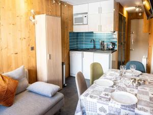 une cuisine avec une table et des chaises et une cuisine avec des armoires blanches dans l'établissement Appartement rénové Val Thorens - 4 pers, 2 chambres, balcon, plein cœur, proximité pistes, commerces - FR-1-637-35, à Val Thorens