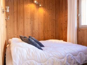 un lit dans une chambre avec un mur en bois dans l'établissement Appartement rénové Val Thorens - 4 pers, 2 chambres, balcon, plein cœur, proximité pistes, commerces - FR-1-637-35, à Val Thorens
