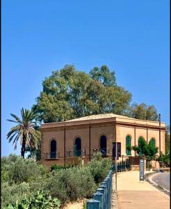 Un edificio de ladrillo con una palmera detrás. en A casa di Mammì nella Valle dei templi, en Agrigento