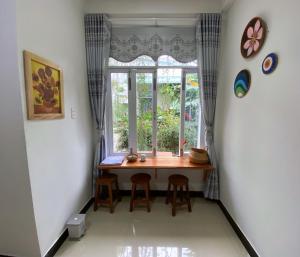uma mesa de jantar com bancos em frente a uma janela em Kontum Home Sweet Homestay em Kon Tum